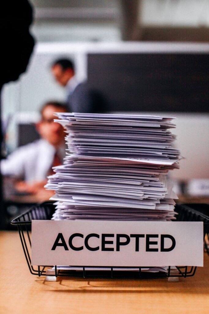 Services Pile of papers with 'Accepted' label in a busy office setting, highlighting information management.