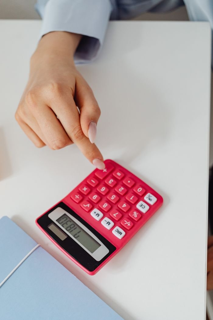 Services A person using a pink calculator on a white desk. This close-up captures precision in accounting work.
