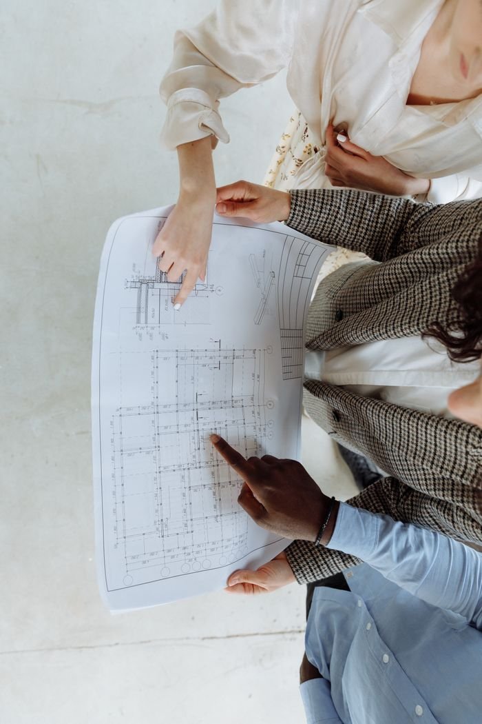 Home High-angle view of diverse team analyzing architectural blueprint indoors.